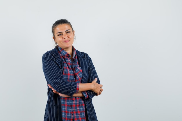 Señora de pie con los brazos cruzados en camisa, chaqueta y mirando confiada. vista frontal.