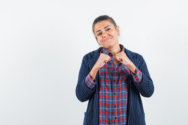 Señora de pie en pose de lucha en camisa, chaqueta y mirando confiada. vista frontal.