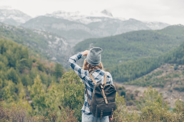 Foto gratuita señora de pie y tomando fotos de montañas en la naturaleza con sombrero gris y jeans durante el día