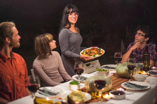 Señora con plato junto a mesa con gente