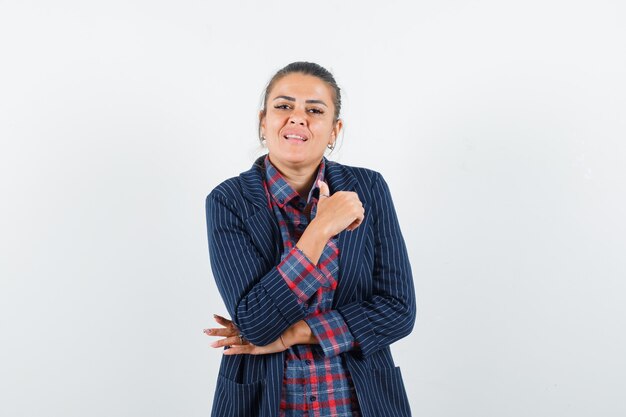 Señora posando mientras está de pie en camisa, chaqueta y luciendo orgullosa, vista frontal.