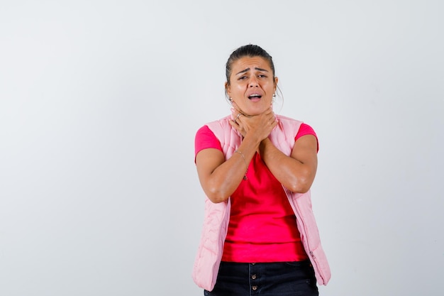 Señora que sufre de dolor de garganta en camiseta, chaleco y aspecto enfermo