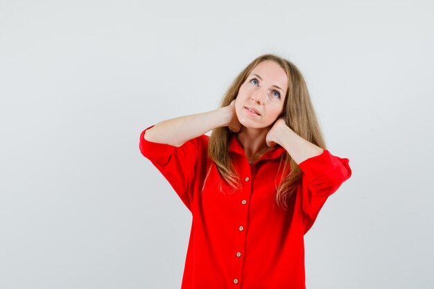 Señora que tiene dolor de cuello en camisa roja y parece cansado,