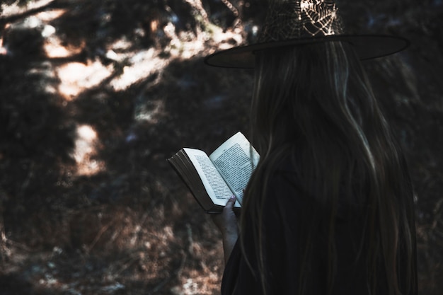 Señora en ropa de bruja leyendo libro