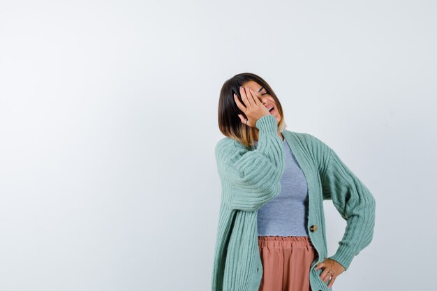 Señora en ropa casual manteniendo la mano en la cara y mirando relajado, vista frontal.