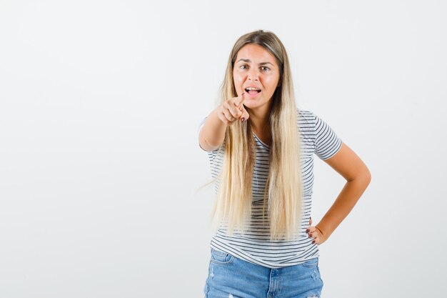 Señora rubia apuntando al frente en camiseta y luciendo estresante