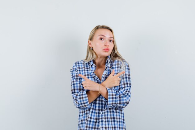 Señora rubia en camisa a cuadros apuntando hacia afuera y mirando perplejo