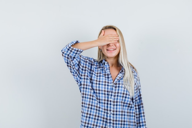 Foto gratuita señora rubia en camisa a cuadros sosteniendo la mano en los ojos y mirando emocionado