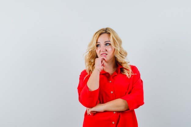 Señora rubia con camisa roja mirando a un lado y mirando confuso espacio para texto