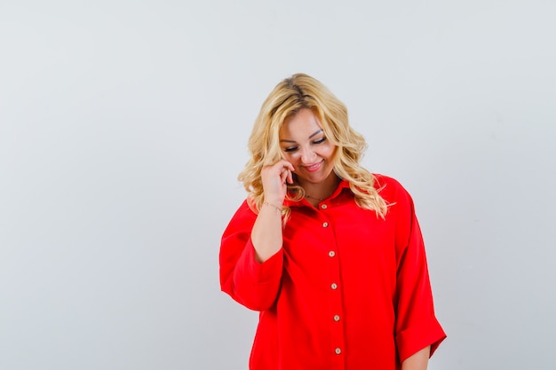 Señora rubia en camisa roja sonriendo y mirando tímido espacio para texto