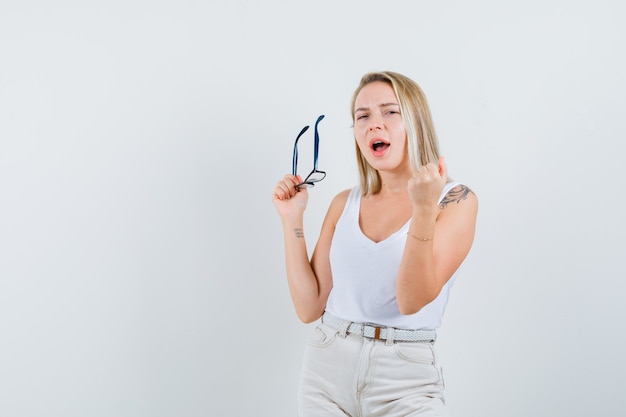 Señora rubia en camiseta, pantalones con gafas y con suerte, vista frontal.