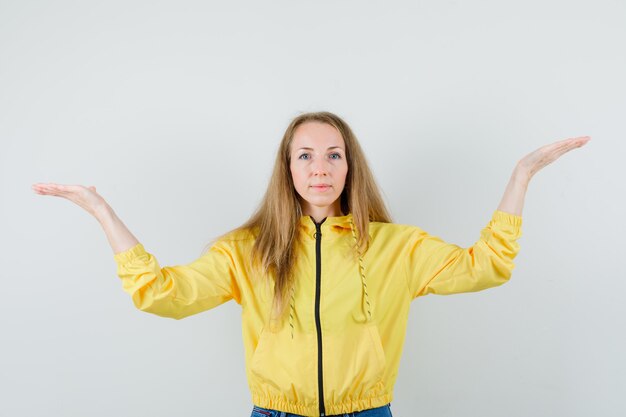 Señora rubia en chaqueta, jeans haciendo gesto de escalas y mirando confiado,