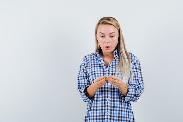 Señora rubia fingiendo usar el teléfono móvil en camisa a cuadros y mirando sorprendido