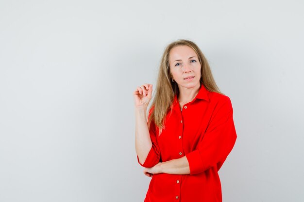 Señora rubia mirando a la cámara en camisa roja y mirando pensativo,