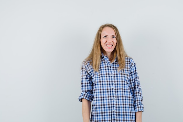 Señora rubia mirando a la cámara con los dientes apretados en camisa