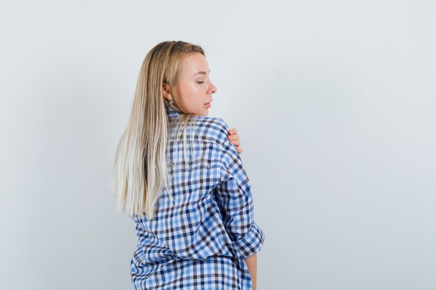 Señora rubia mirando por encima del hombro en camisa casual y elegante, vista posterior.