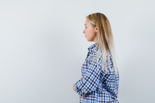 Señora rubia mirando a otro lado en camisa casual y mirando tranquila.