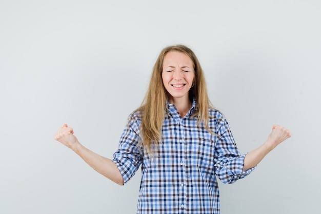 Señora rubia mostrando gesto de ganador en camisa y con suerte,