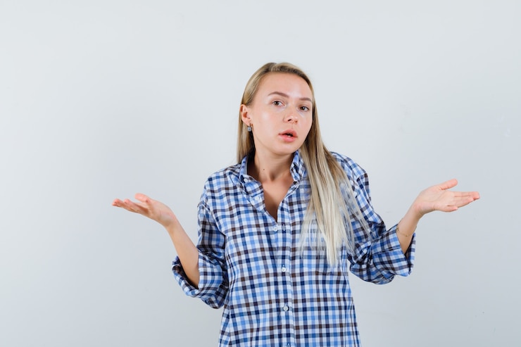 Foto gratuito señora rubia mostrando gesto de impotencia en camisa a cuadros y mirando confundido