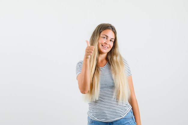 Señora rubia mostrando el pulgar hacia arriba en camiseta y mirando satisfecho, vista frontal.