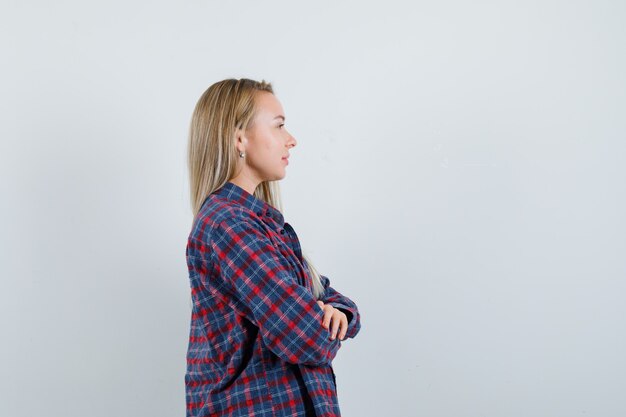 Señora rubia de pie con los brazos cruzados en camisa casual y con aspecto optimista.