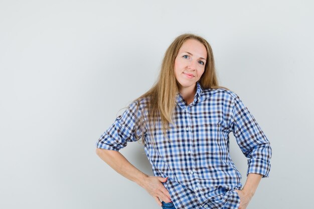 Señora rubia posando mientras está de pie en camisa y se ve fascinante.