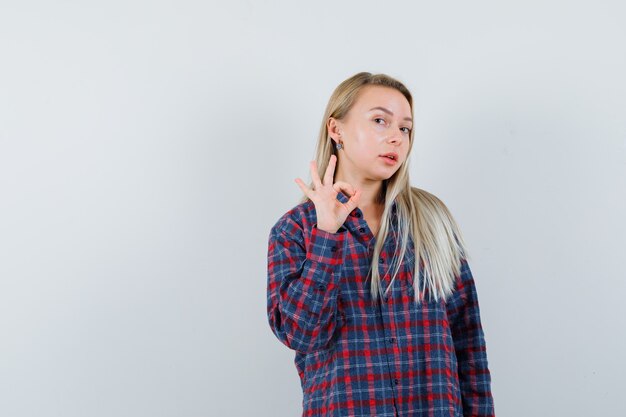 Señora rubia que muestra un gesto aceptable en camisa casual y que parece confiada. vista frontal.