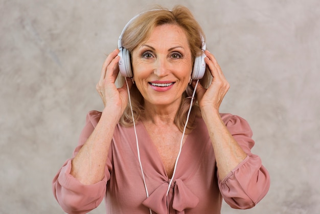 Señora rubia sonriente escuchando música en el set de auriculares