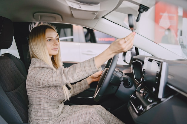 Señora en un salón de autos. Mujer comprando el coche. Mujer elegante con un traje marrón.