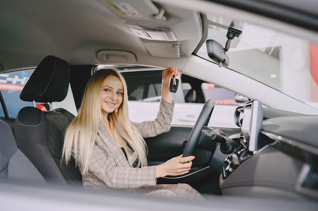 Señora en un salón de autos. Mujer comprando el coche. Mujer elegante con un traje marrón.