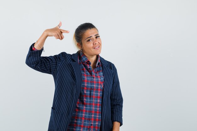 Señora señalando a sí misma en camisa, chaqueta y luciendo orgullosa. vista frontal.