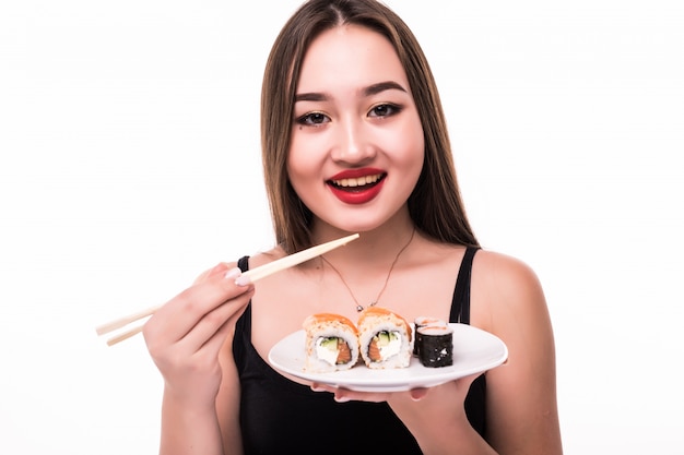 Foto gratuita señora sonriente con cabello negro y labios rojos probar los rollos de suushi con palillos de madera en la mano