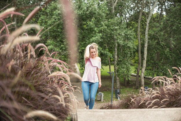 Señora sonriente caminando en el parque de la ciudad