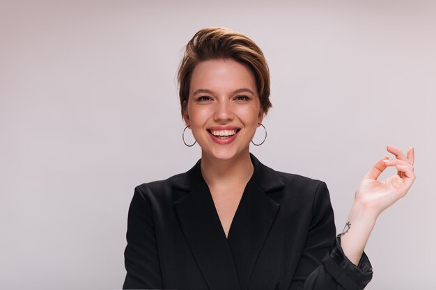 Señora sonriente en chaqueta negra posando sobre fondo aislado. Feliz mujer alegre en traje oscuro riendo y mirando a la cámara