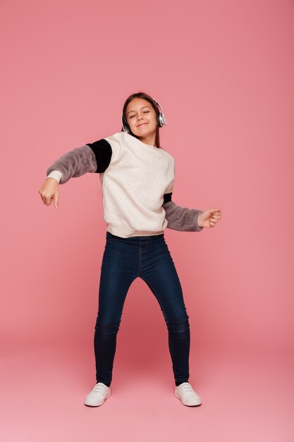 Señora sonriente divertida bailando mientras escucha música en auriculares