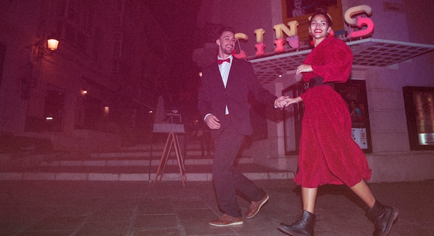 Foto gratuita señora sonriente hermosa que camina con el individuo positivo joven en la calle por la tarde