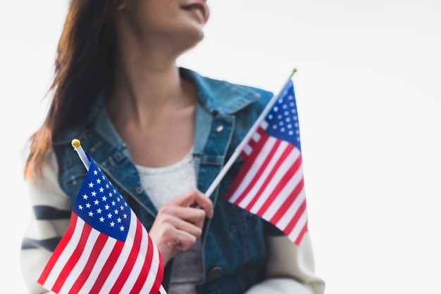 Señora sonriente joven que sostiene banderas americanas