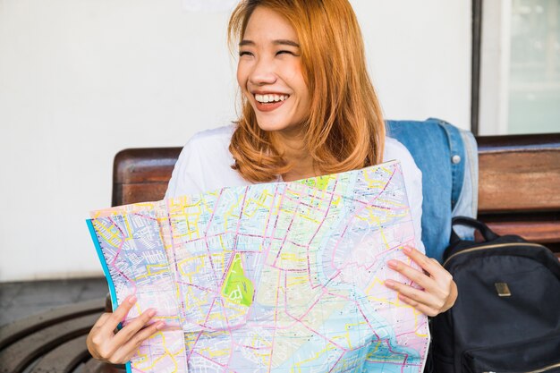 Señora sonriente con el mapa en el banco