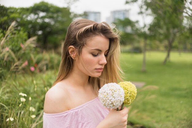 Señora sosteniendo flores brillantes en el parque de la ciudad