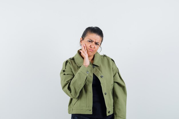 Señora sosteniendo la mano en la mejilla en la chaqueta