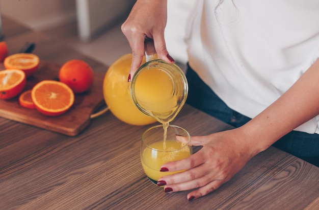 Señora vertiendo jugo de naranja en la cocina