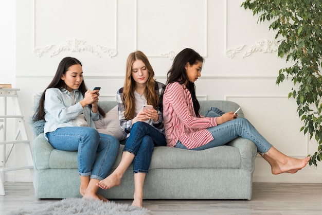 Señoras sentadas en el sofá y cargadas en los teléfonos