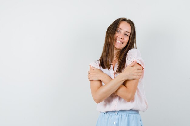 Señorita abrazándose a sí misma en camiseta, falda y buscando amada. vista frontal.