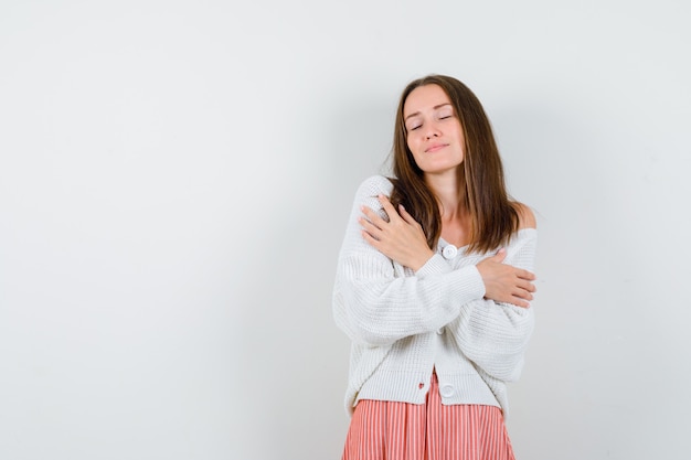 Foto gratuita señorita abrazándose a sí misma en chaqueta de punto y falda con sueño aislado