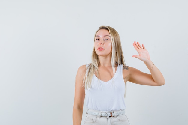 Señorita agitando la mano para despedirse en blusa blanca.