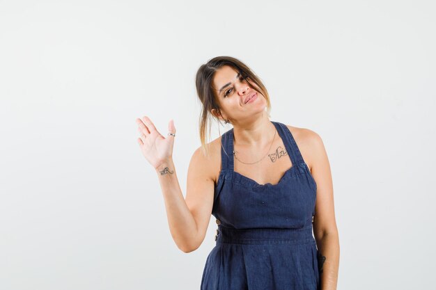 Señorita agitando la mano para saludar en vestido y mirando alegre