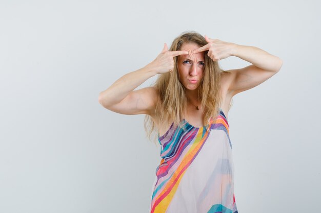 Señorita apretando su grano en la frente en vestido de verano