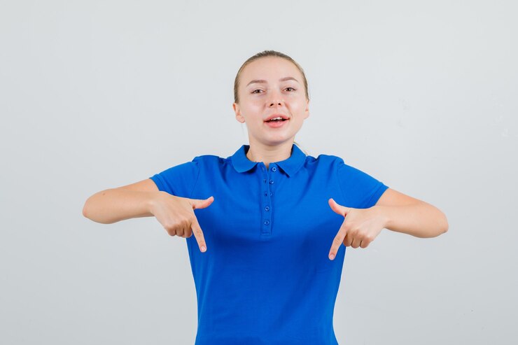 Foto gratuito señorita apuntando hacia abajo en camiseta azul y mirando confiado