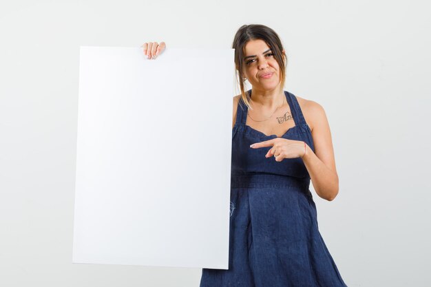 Señorita apuntando al lienzo en blanco vestido y mirando confiado