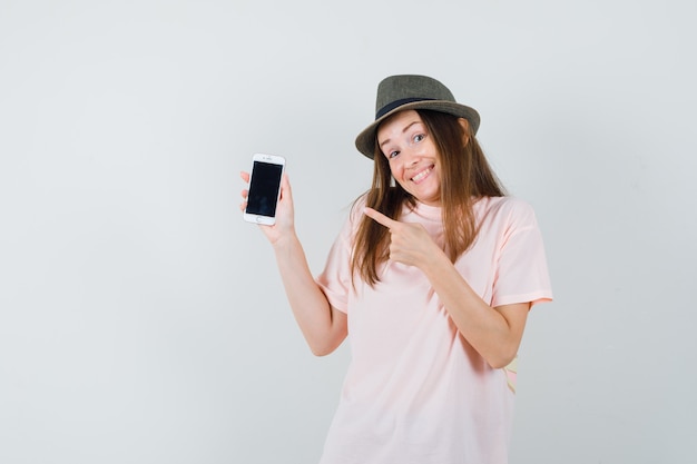 Señorita apuntando al teléfono móvil con sombrero de camiseta rosa y mirando lindo